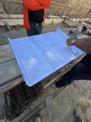 Construction drawings being reviewed over timber forms on the NEIGHBOUR 1 site